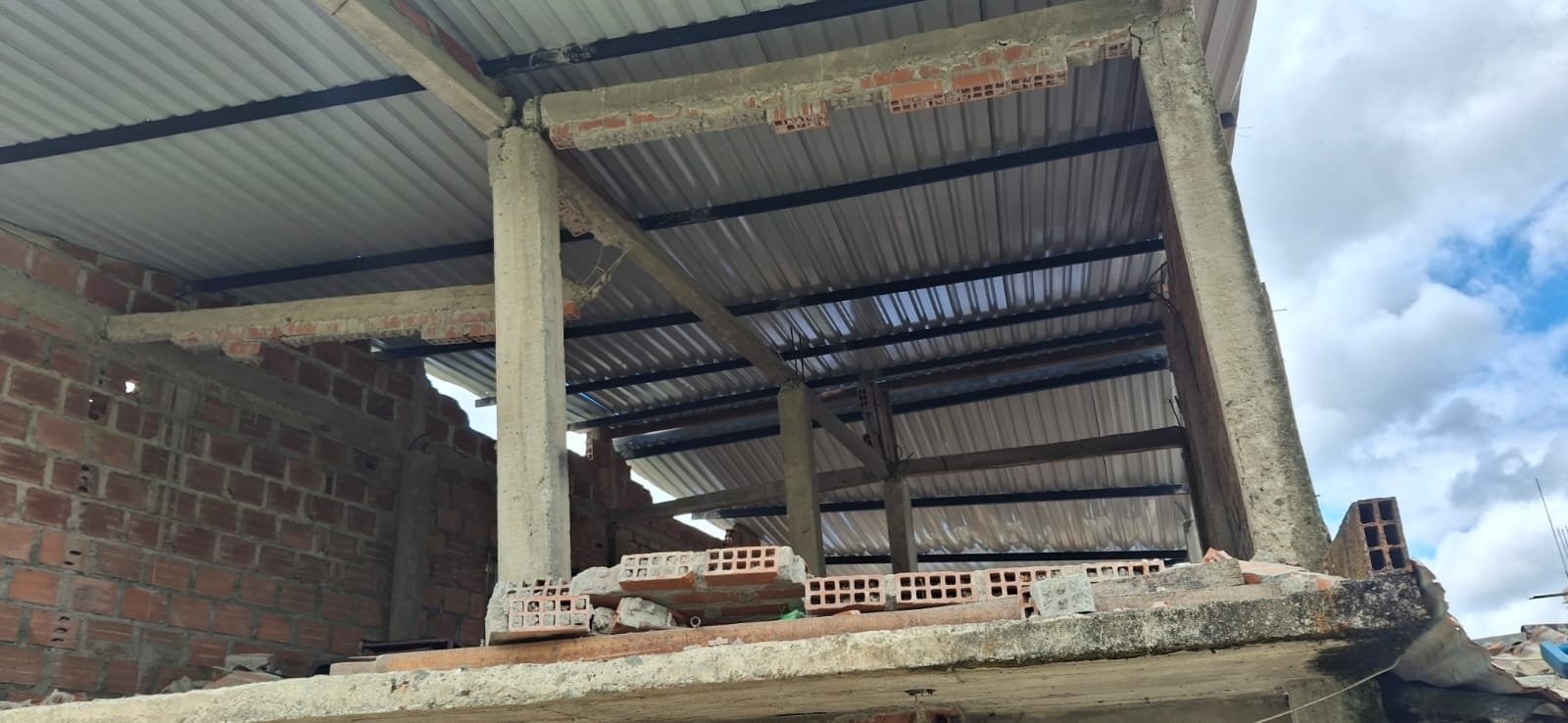 Estructura de techo y columnas con ladrillos sueltos apilados