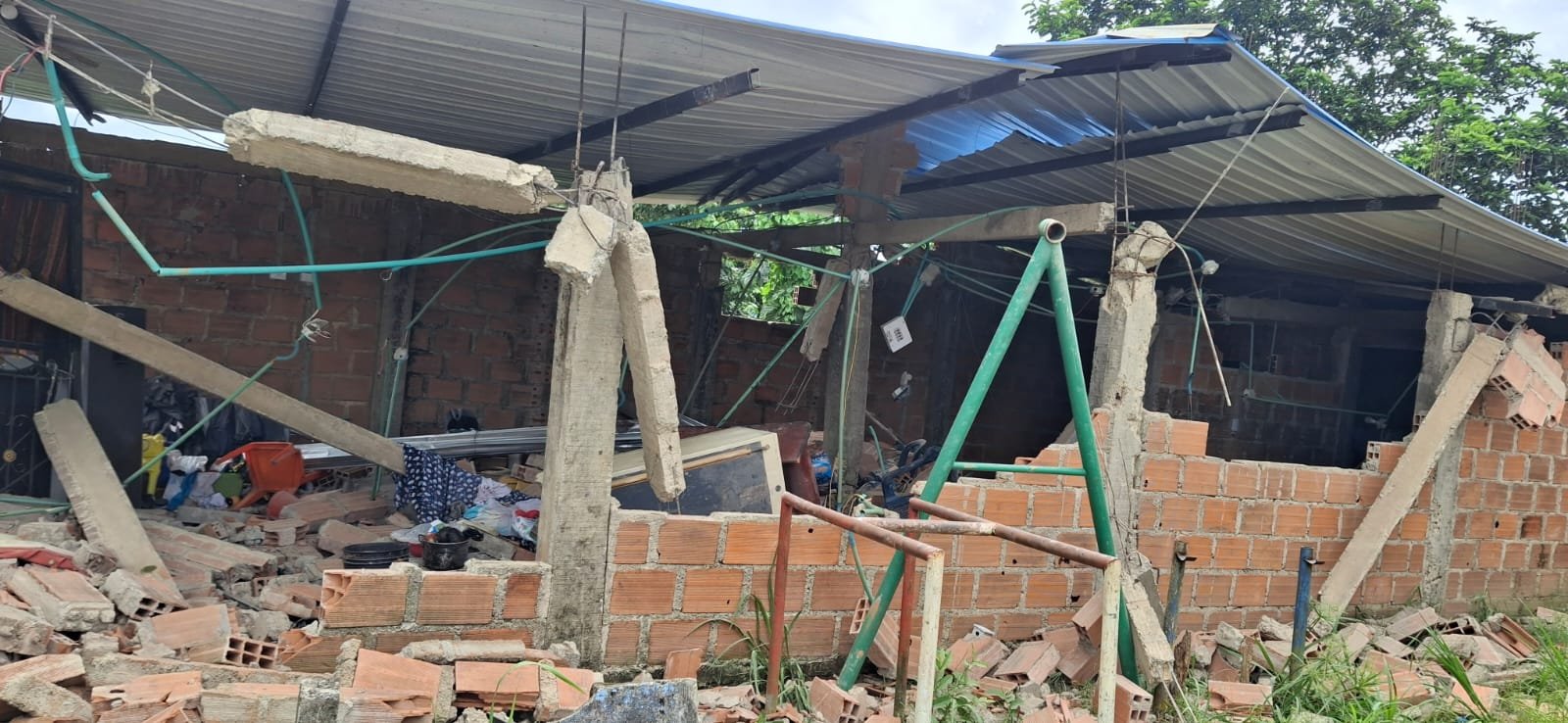 Vivienda de Citronela con el techo y una pared colapsados tras el sismo, vigas y cables expuestos entre los escombros