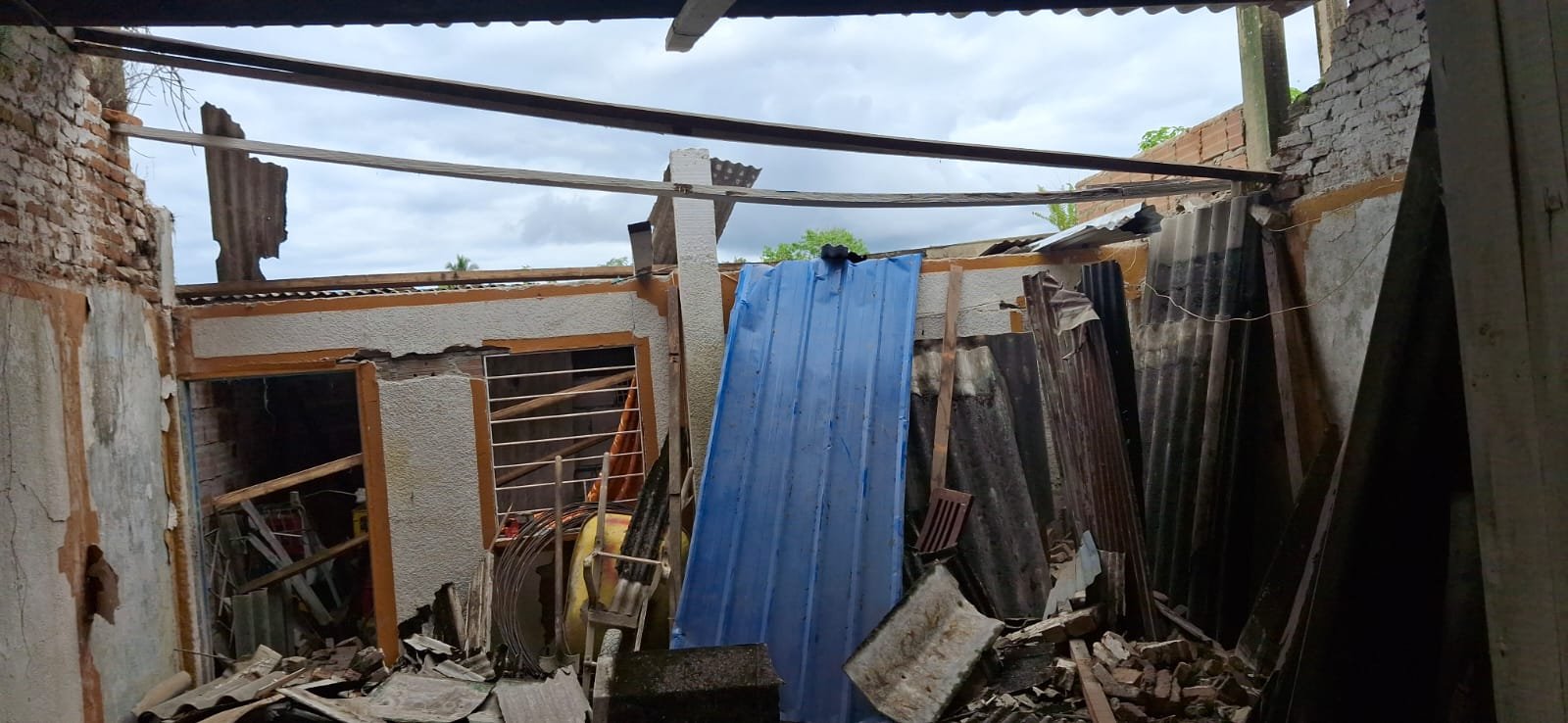 Techo colapsado con láminas y escombros dentro de la vivienda
