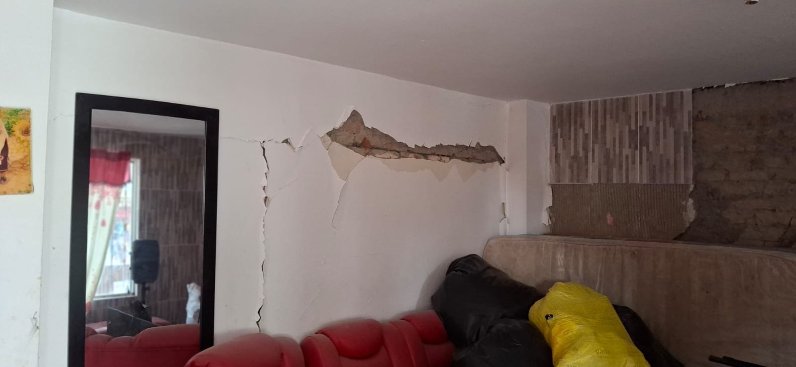 Grieta y desprendimiento de estuco en la pared de la sala