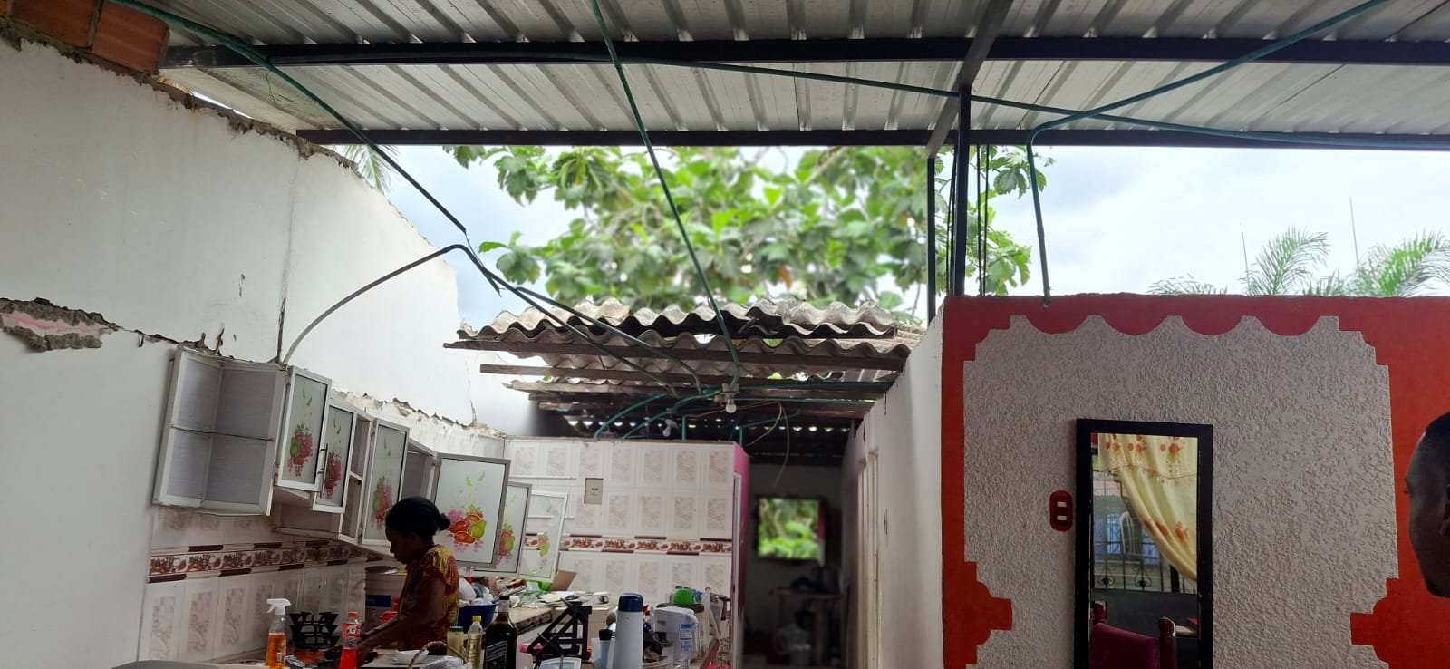 Familia en la cocina de su vivienda, con grietas en pared y techo parcialmente desprendido